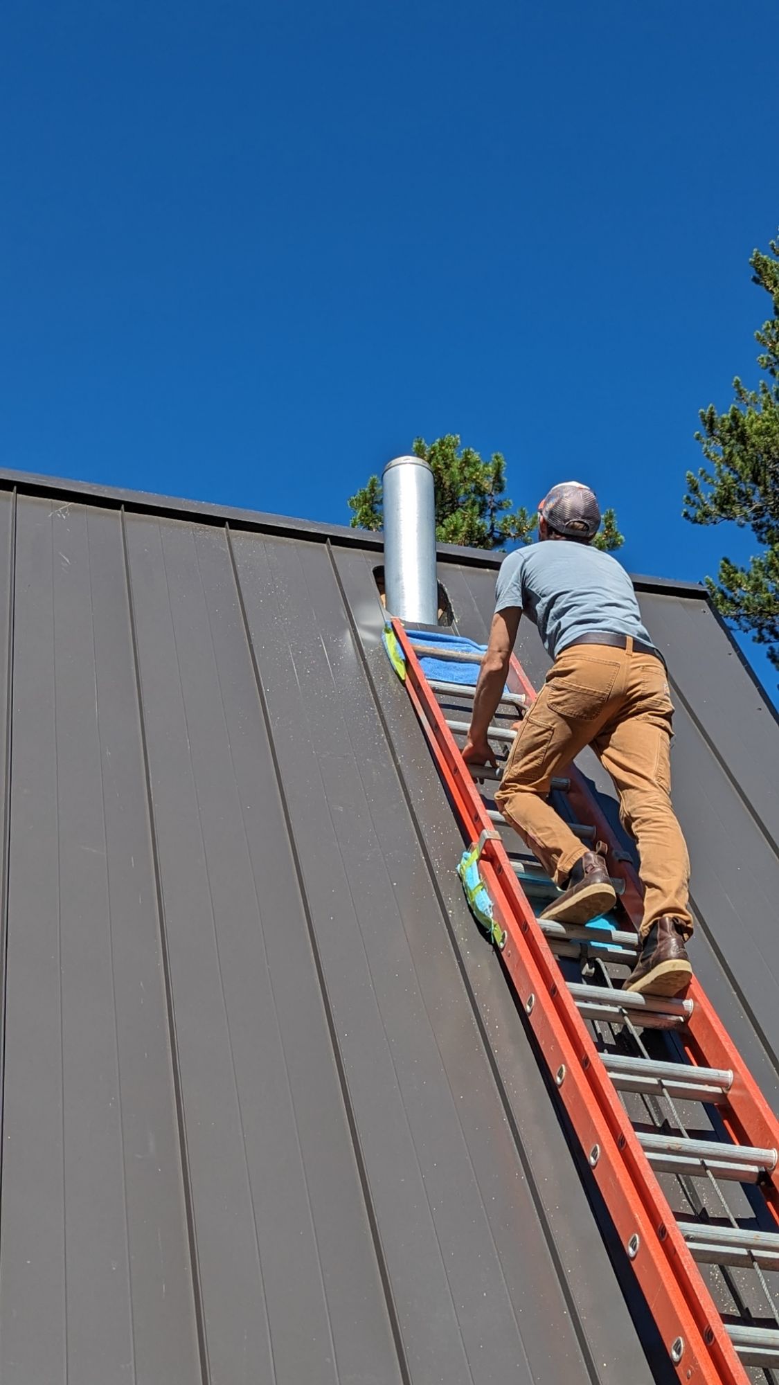 Photo of man installing chimney for wood stove in cabin.