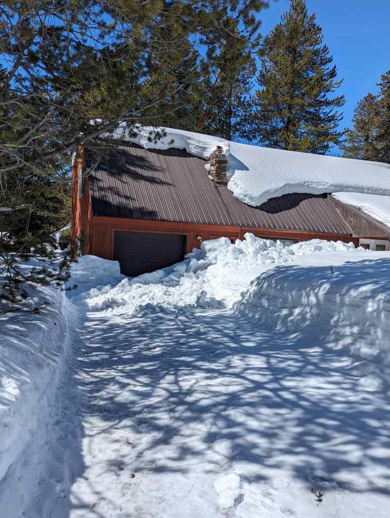 Photo of roof avalanche blocking garage door is the sign of poor cabin roof design.
